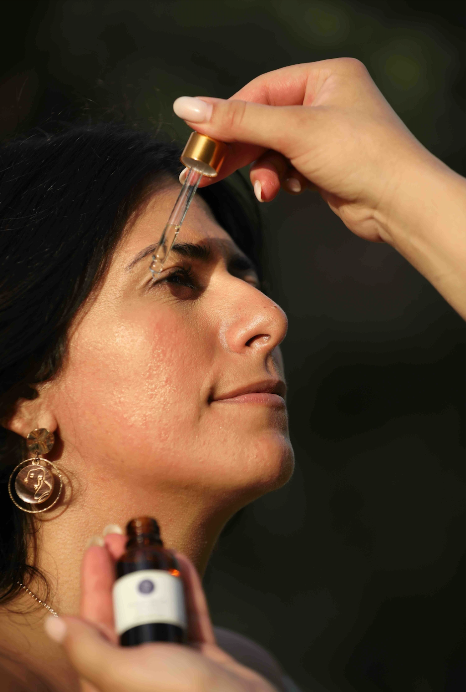 Woman using dropper to apply facial oil to face